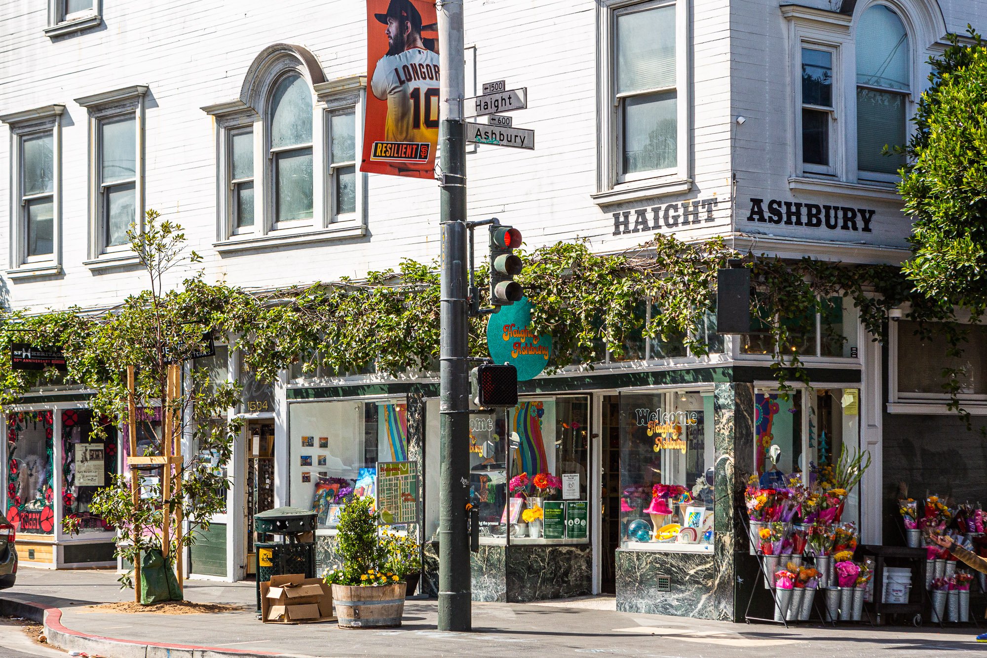 Haight and Ashbury street corner with shops, colorful storefronts, and floral decorations.