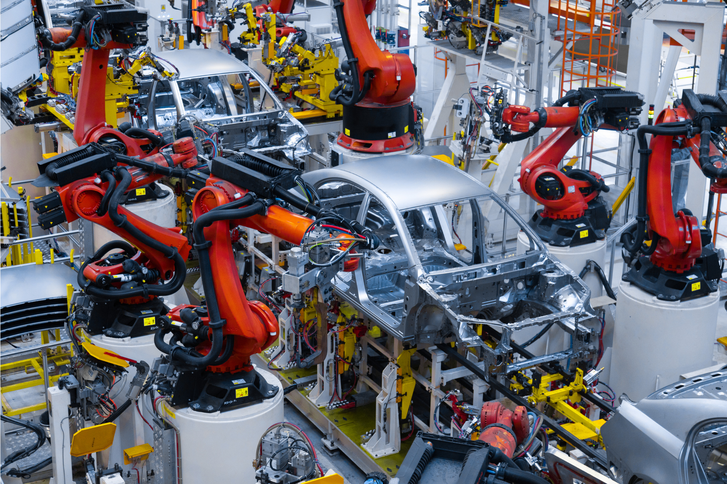 Robotic arms assembling car frames in an automotive factory.