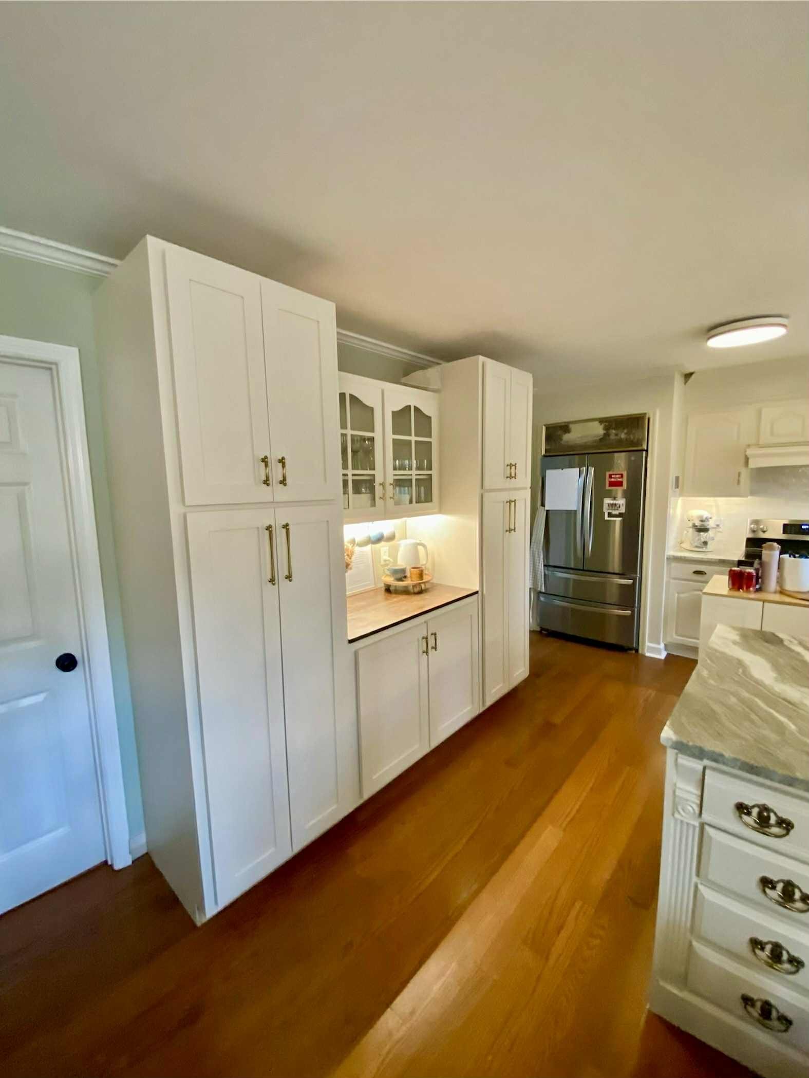 Kitchen with white cabinets, a microwave, a refrigerator, and a marble countertop.