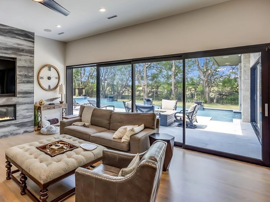 room with fireplace and large sliding glass doors that go across the whole wall with a view of outside and pool