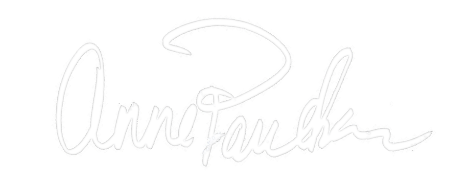 Signature or stylized logo reading 'Ann Faucheux' with a decorative swirl above the name, all in white.