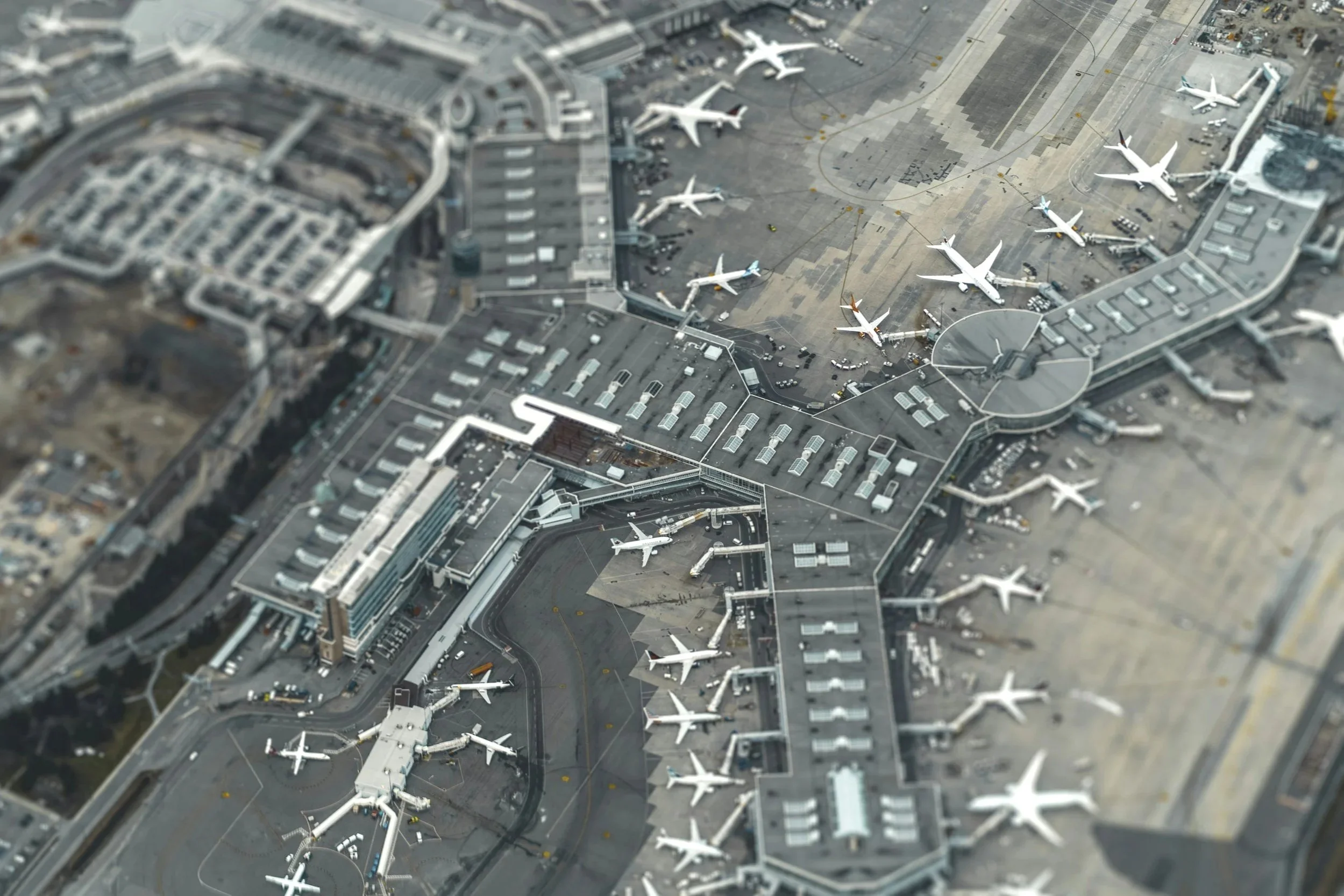 a bird's-eye view of an airport with dozens of planes waiting at the gate. Airports act as important travel hubs.