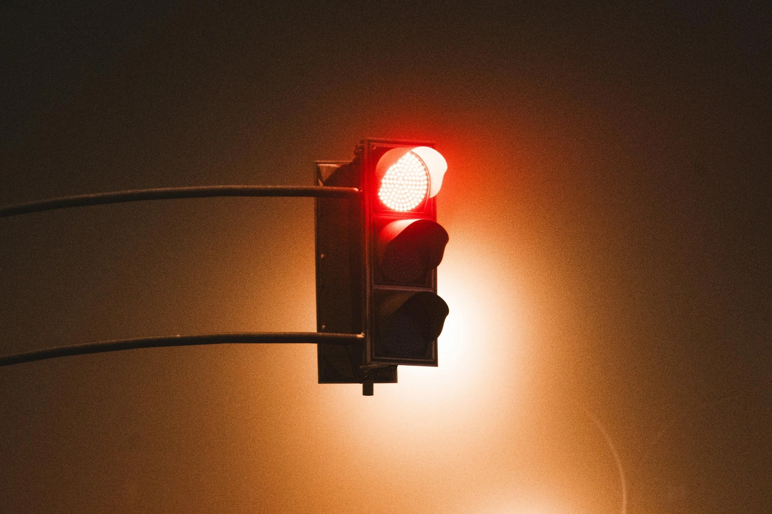 A traffic signal shows red in fog.