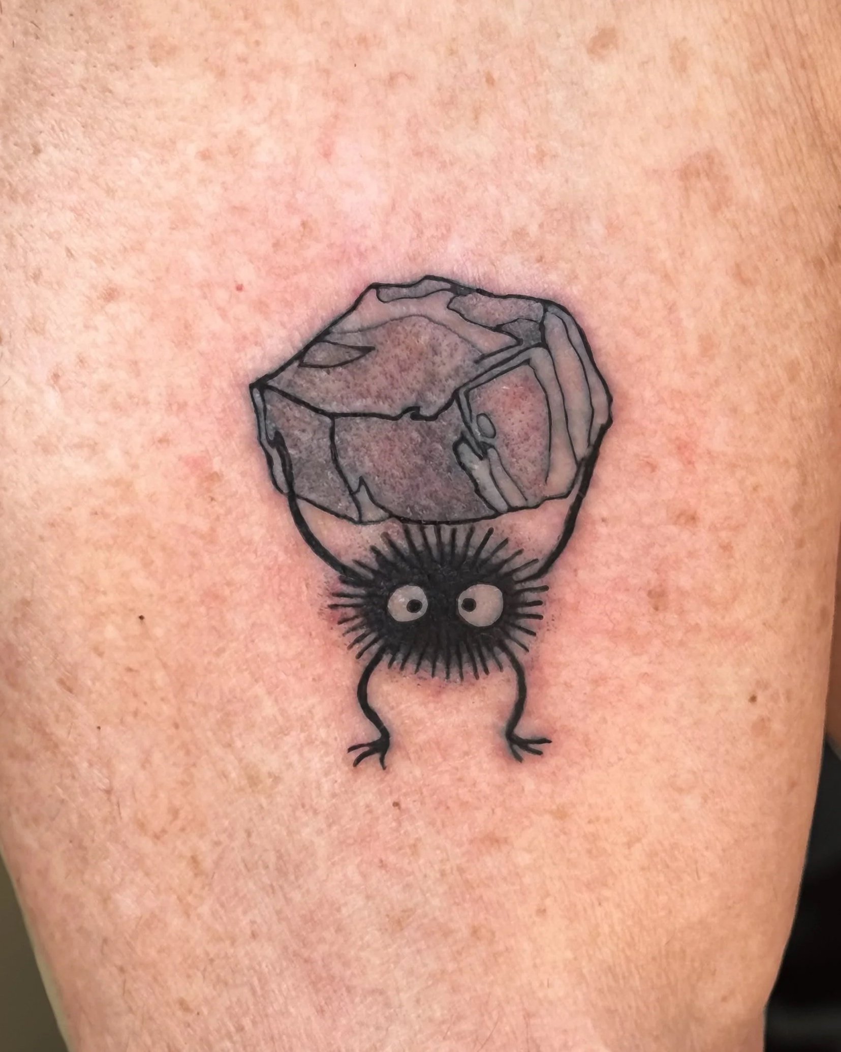 Tattoo of a dice and a spider with eyes on a person's arm.