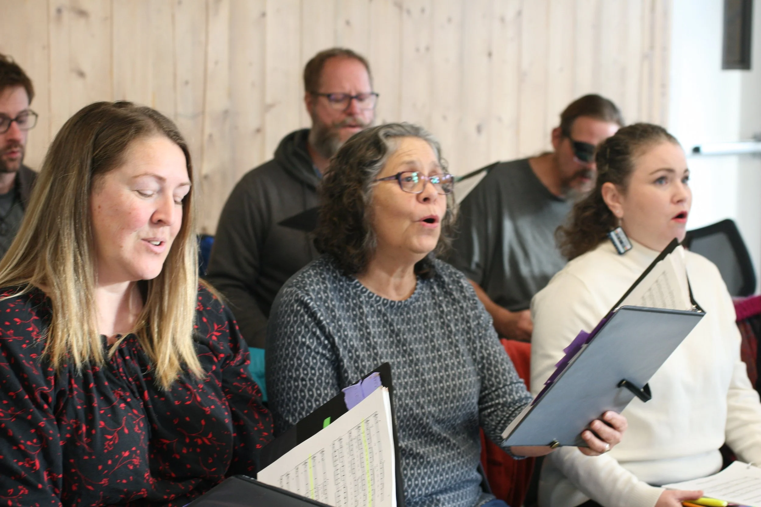 Group of people singing in choir, holding sheet music