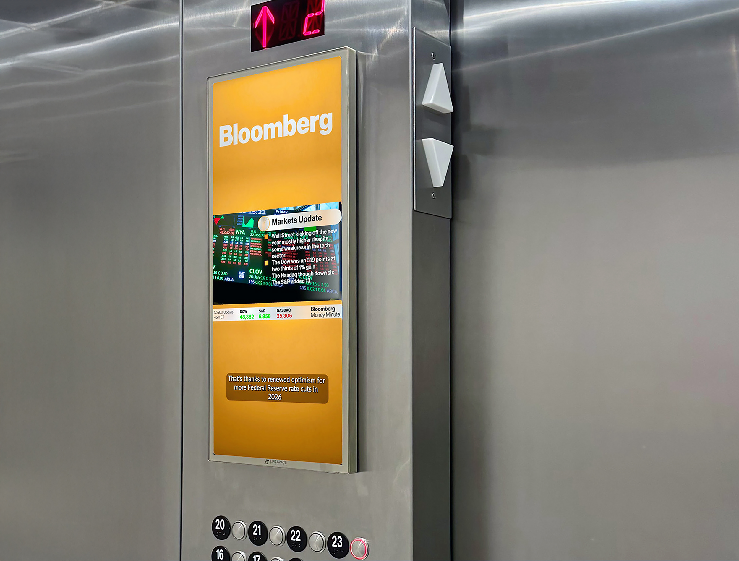 Midsize digital display in an elevator, displaying market news from Bloomberg.