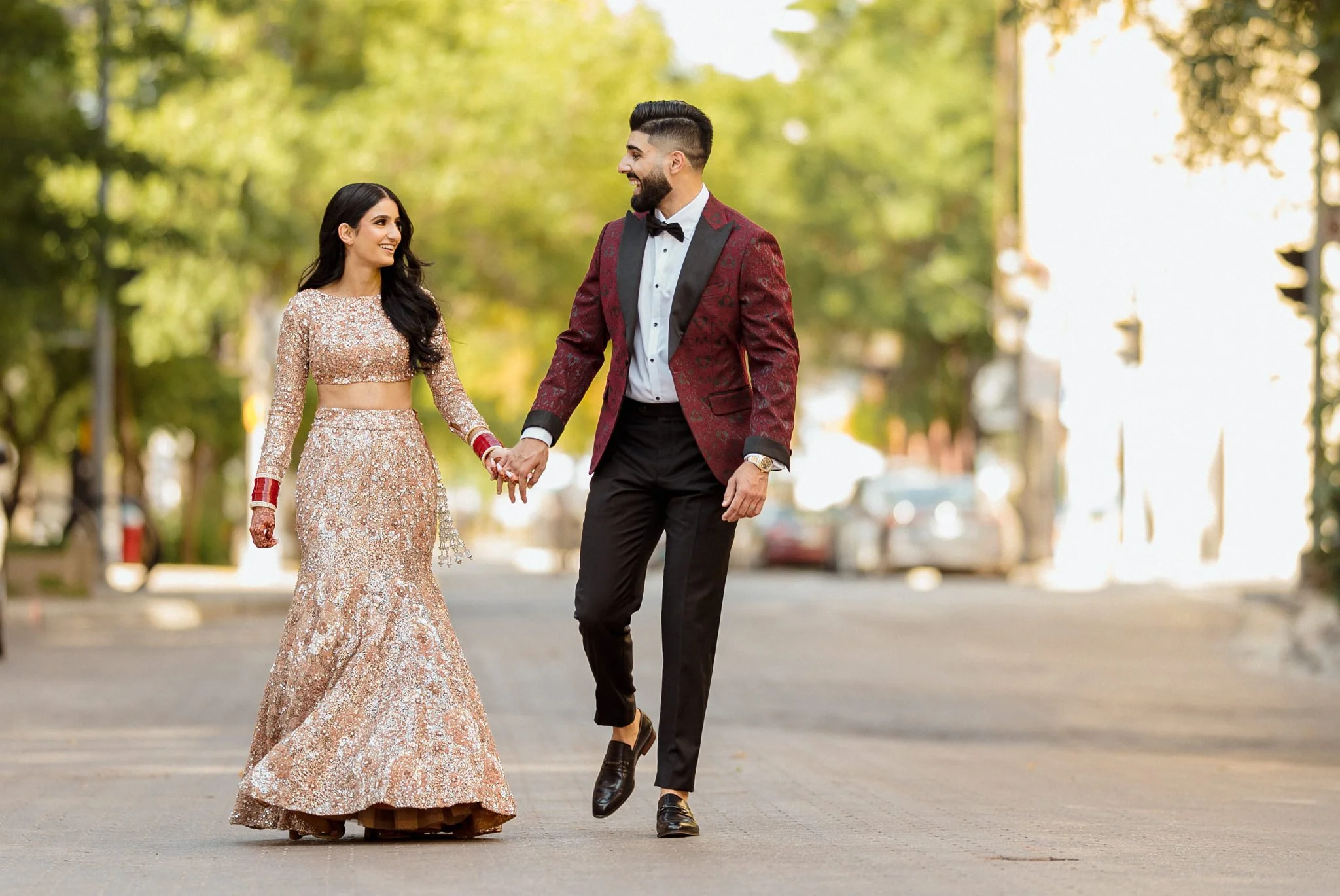 Couple walking hand in hand before their wedding reception smiling at each other