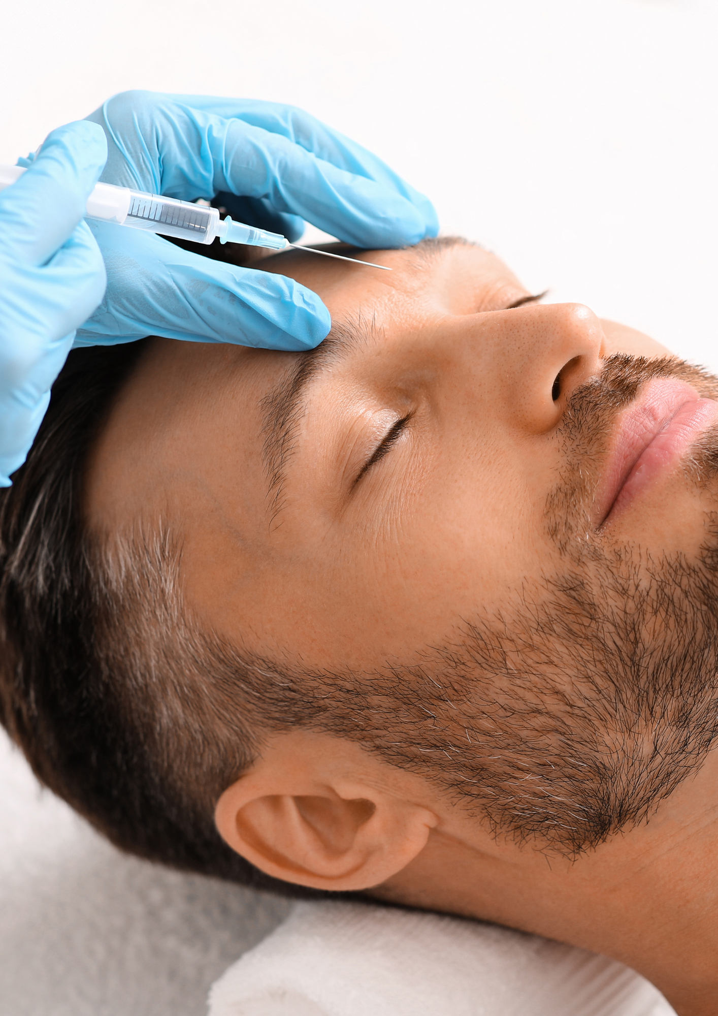 A man receiving a cosmetic treatment or injection on his forehead from a medical professional wearing blue gloves.