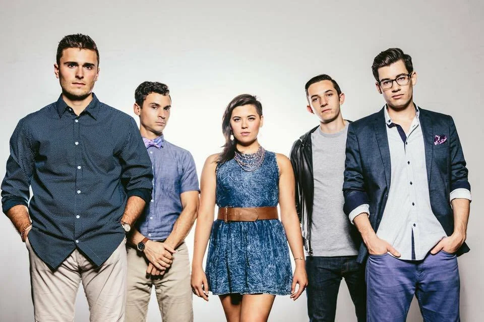 Switch Vocals, a 5-person acappella group featuring Sean Switzer, Noah Berg, Marianne, Andy Degan, and Colin Egan. 

 A group of five young adults, three men and two women, standing together against a plain light background, each with serious express