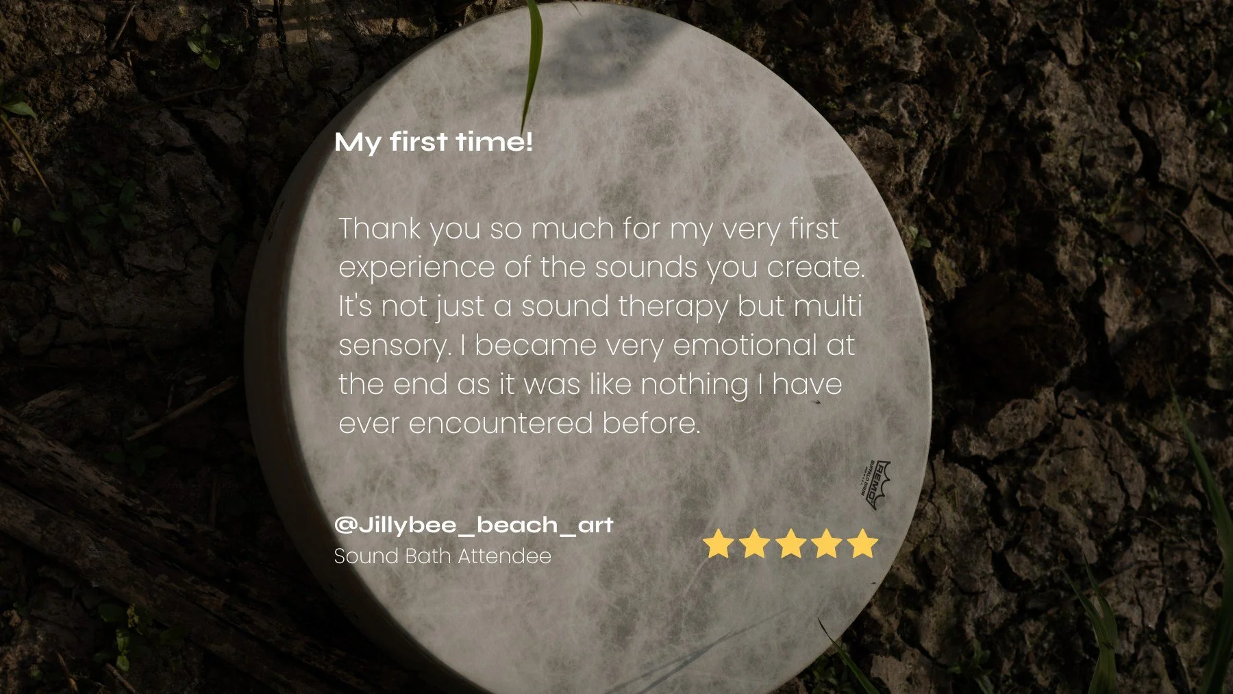 A Remo buffalo drum with a 5 star review thank you message inscribed on it, placed on a soil ground with small green plants and grass around.
