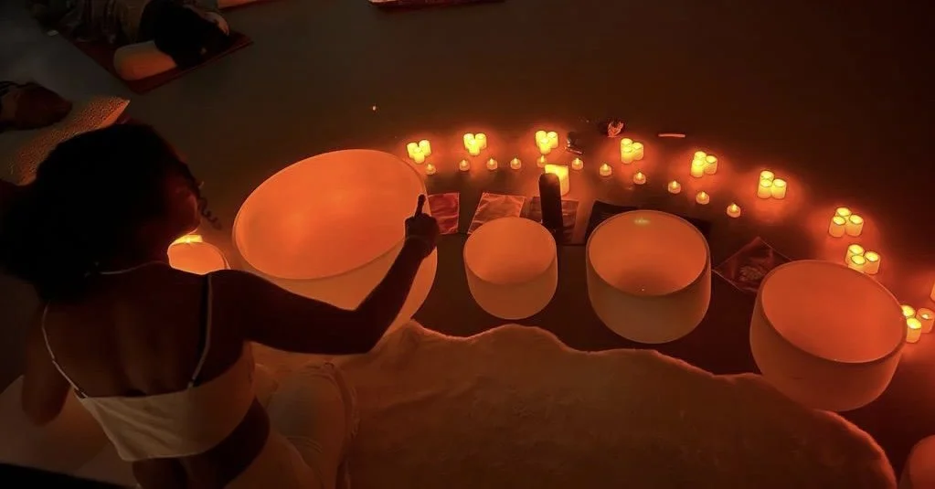 A woman playing crystal singing bowls for a sound bath meditation sessions in Manchester.