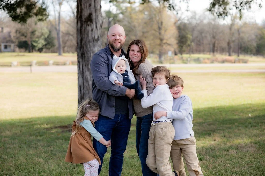 Hysinger Family, Chattanooga,TN smiling and hugging outdoors near a large tree in a park during autumn.