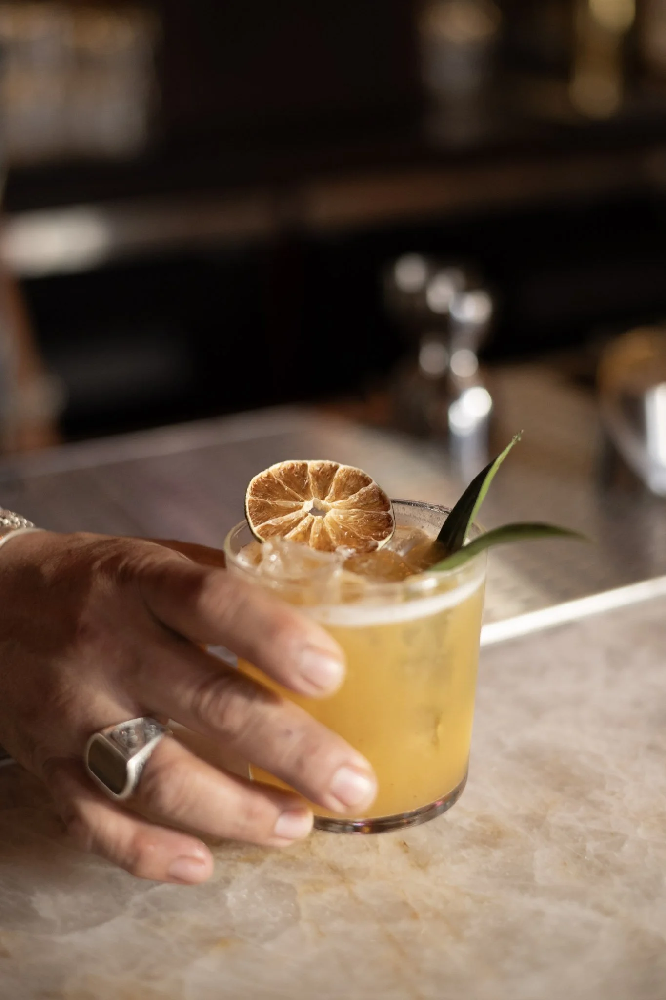 hand holding orange cocktail in short glass