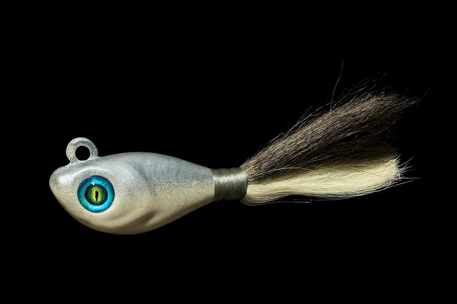 A fishing lure designed to resemble a small creature, with a fish-like head, detailed eye, and a tail made of synthetic fibers.