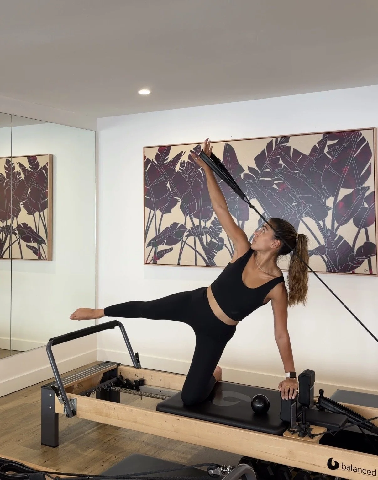 Image of Pilates Teacher Azraa demonstrating a flow in front of the painting As far as I can reach by Kate Valentine