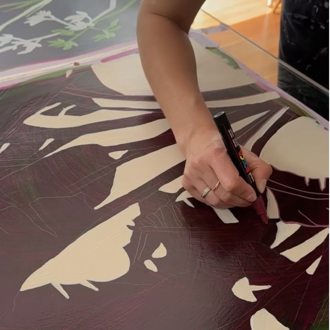 Image of a woman’s hand drawing on on a painted working on paper