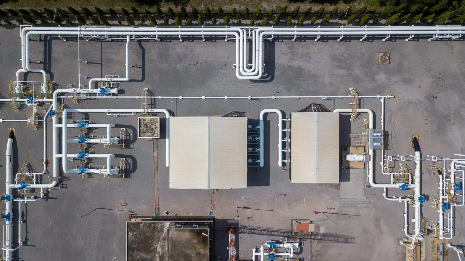 Aerial view of an industrial natural gas pipeline facility featuring interconnected white pipes, valves and processing equipment.