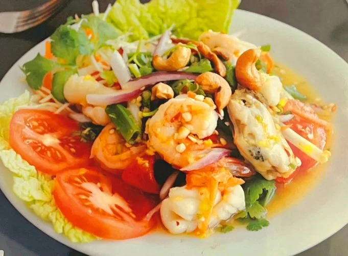 Seafood salad with shrimp, oysters, sliced tomatoes, lettuce, and mixed greens