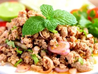 Ground pork salad garnished with fresh mint, lemon, and herbs.