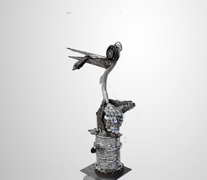 Metal sculpture resembling a bird with long beak and mechanical components on a cylindrical base.