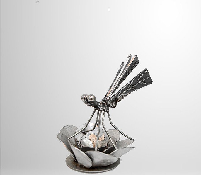 Metal dragonfly sculpture on a lotus flower