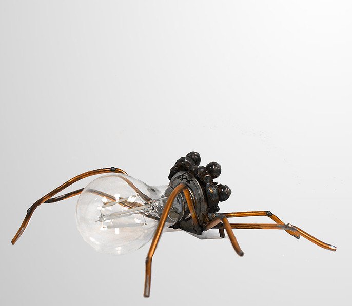 A sculpture of a spider made from metal parts and a light bulb