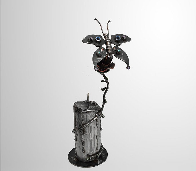 Metal sculpture of a butterfly on a flower with a cylindrical base.
