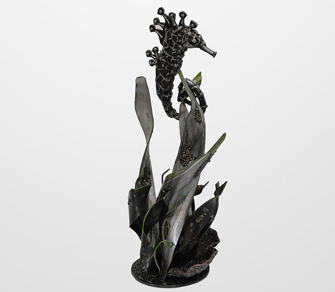 Metal seahorse sculpture with seaweed on white background