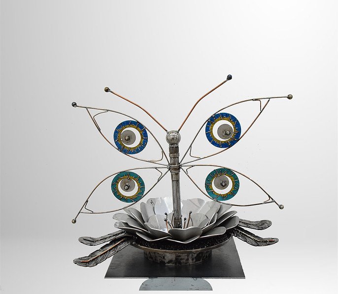 Artistic sculpture of a butterfly made from mechanical parts, with decorative wings and metal flower base.