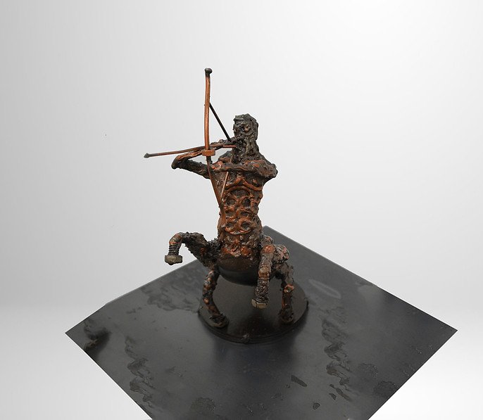 Rustic metal sculpture of a centaur archer on a dark base, viewed from an angle.
