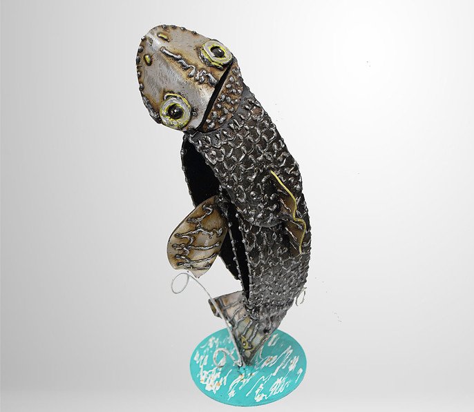 Metal fish sculpture, with textured scales and detailed eyes, mounted on a circular blue base.