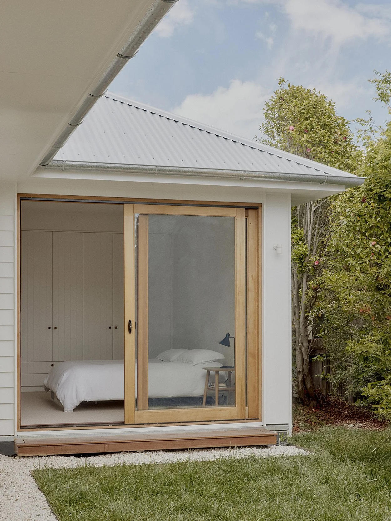 Main bedroom with full-height timber-framed sliding door opening directly onto the private courtyard garde