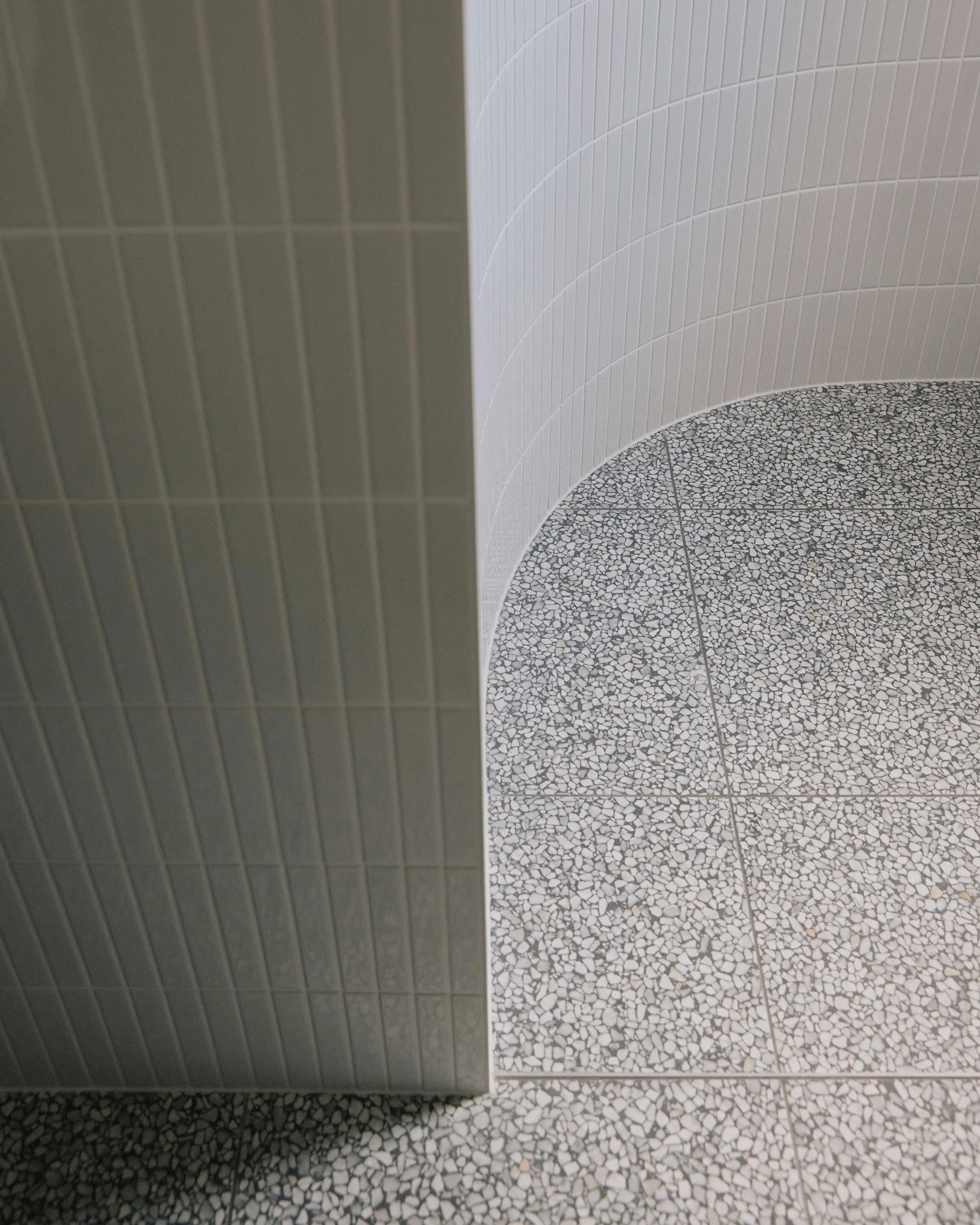 Curved tile detail Berrima bathroom - white tiles terrazzo floor junction ZF Architects