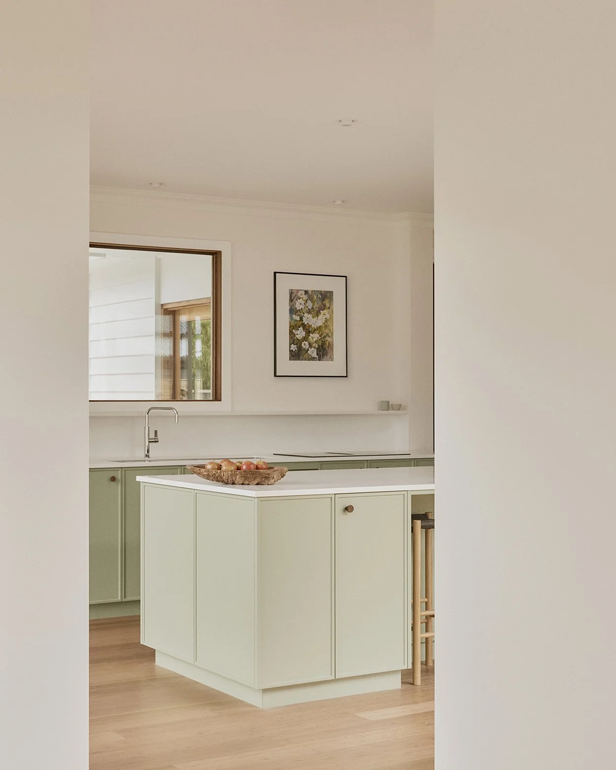 Sage green kitchen island with white stone benchtop, timber floor and framed artwork, Mittagong Courtyard Cottage interior