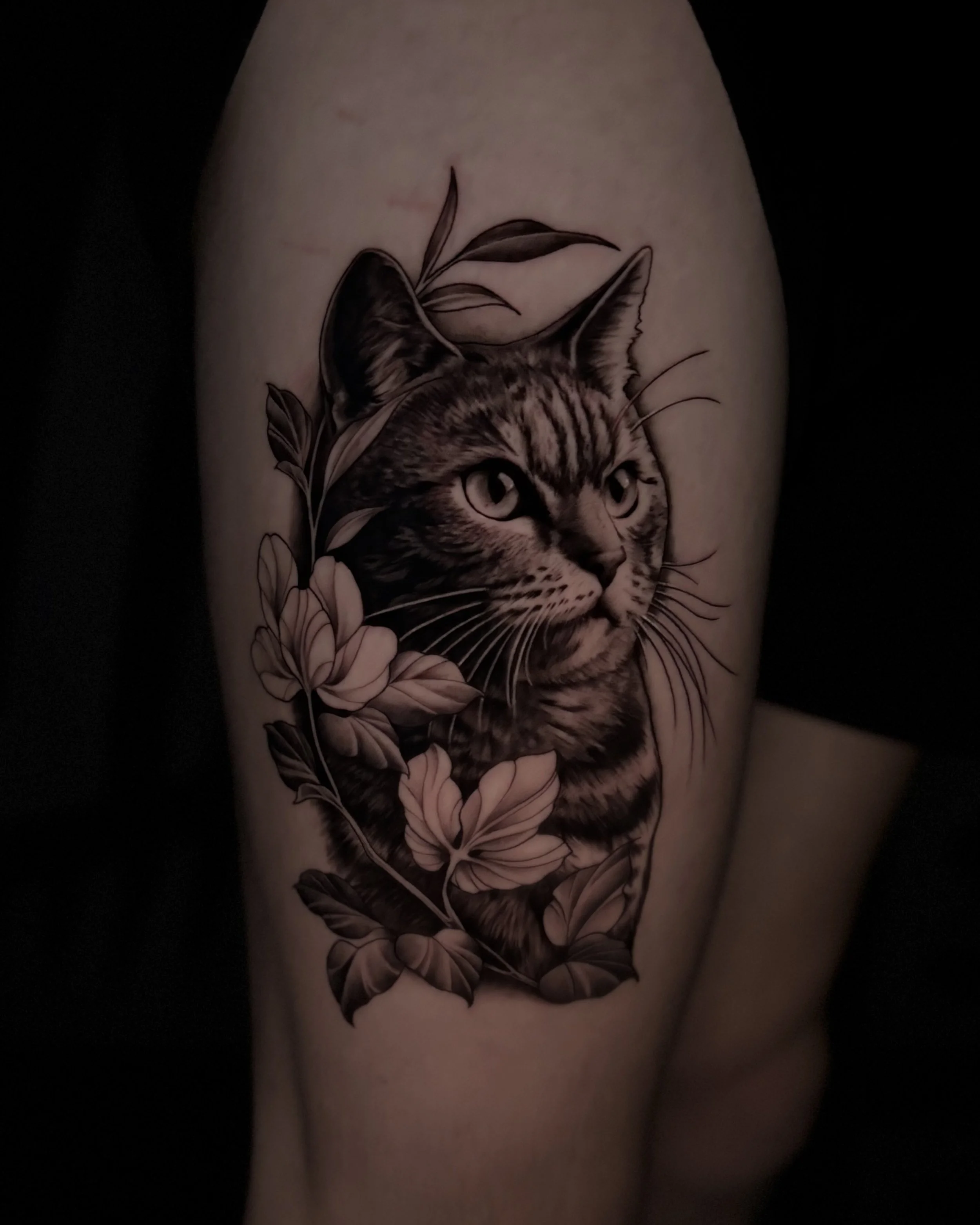 Epic black and grey realism tattoo by Soleya Tattoo in Auckland — beautifully crafted details in this cat portrait accompanied by a delicate vine of florals