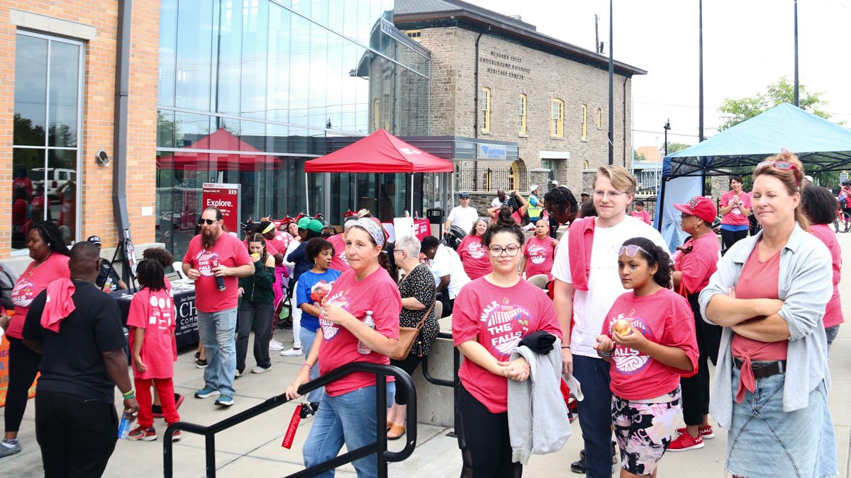 Group of people gathered outdoors and participating in an event with tents and tables.