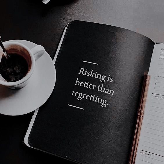 An open book with a quote, a cup of coffee on a saucer, and a pen on a dark surface.