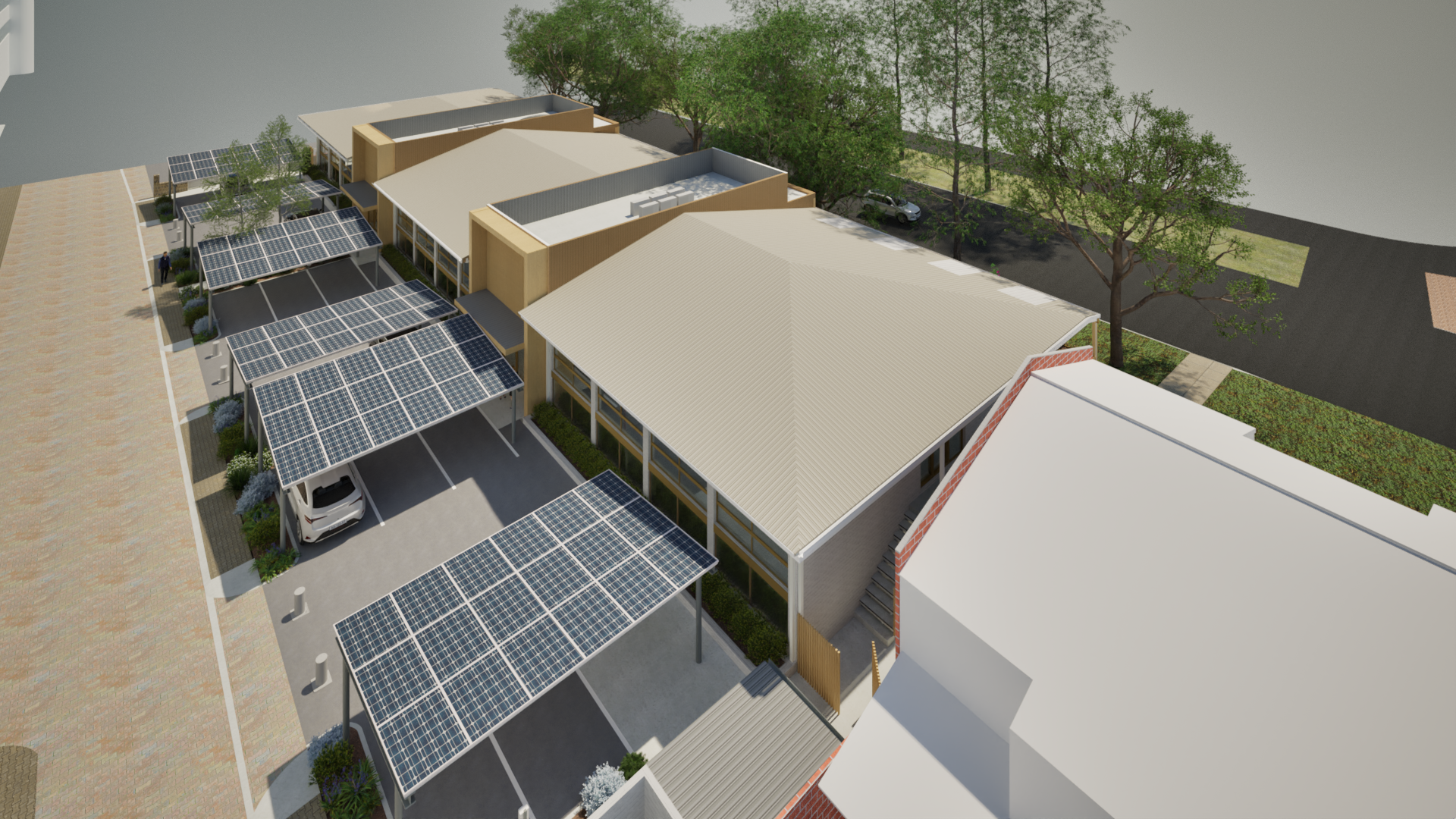 Aerial view of a modern building with solar panels on parking canopies and rooftops, surrounded by trees and a street with a parked car.