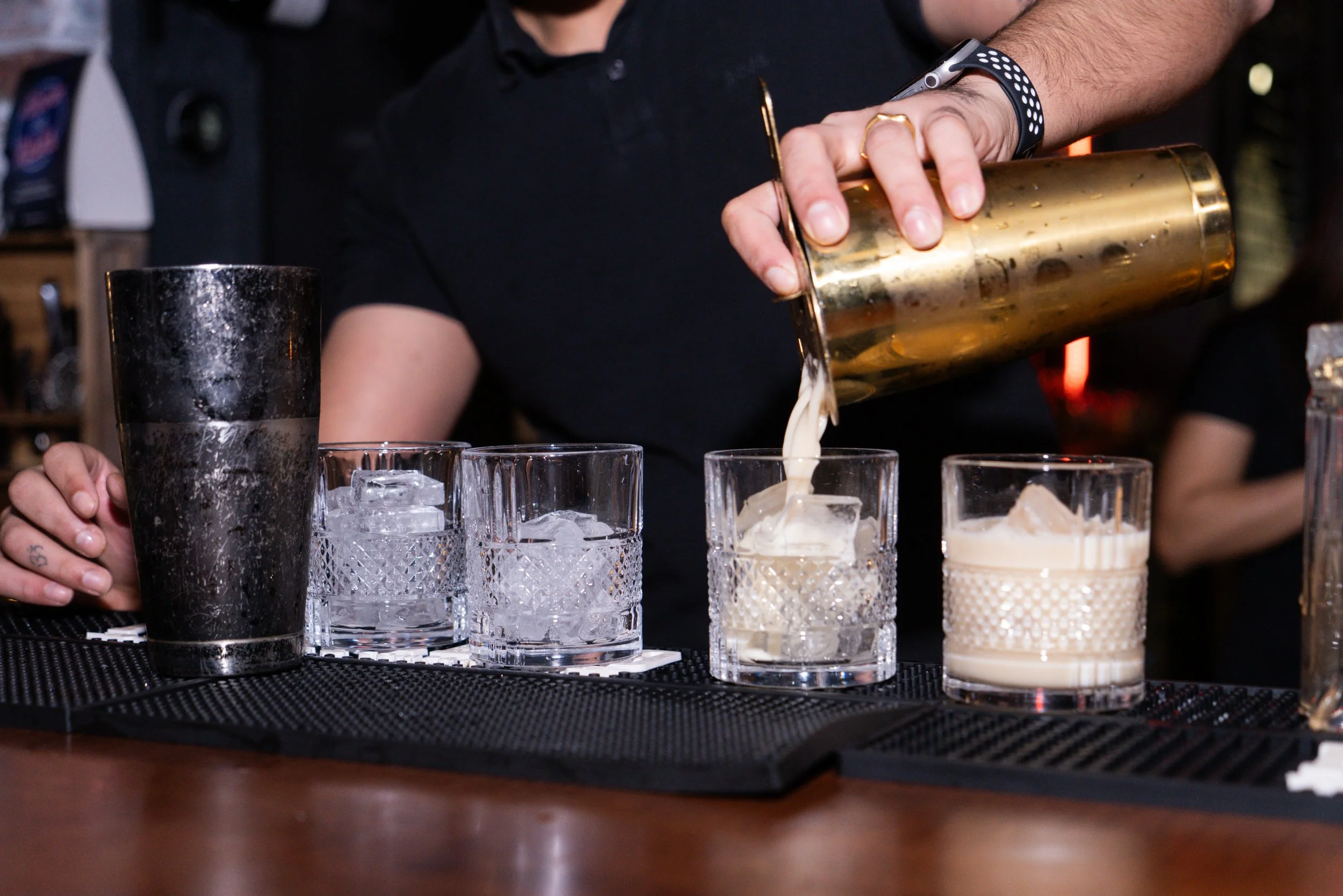 Bartender pouring drink into glass with ice at bar
