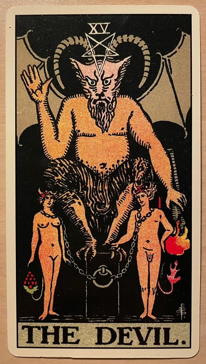 The tarot card of The Devil, with a pitch black background, and he’s an angry, horned, winged and bearded half-man-half-goat.