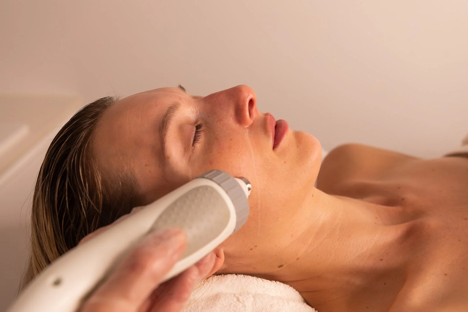 A person undergoing Radio Frequency procedure using a handheld ultrasound device on their face to tighten skin.