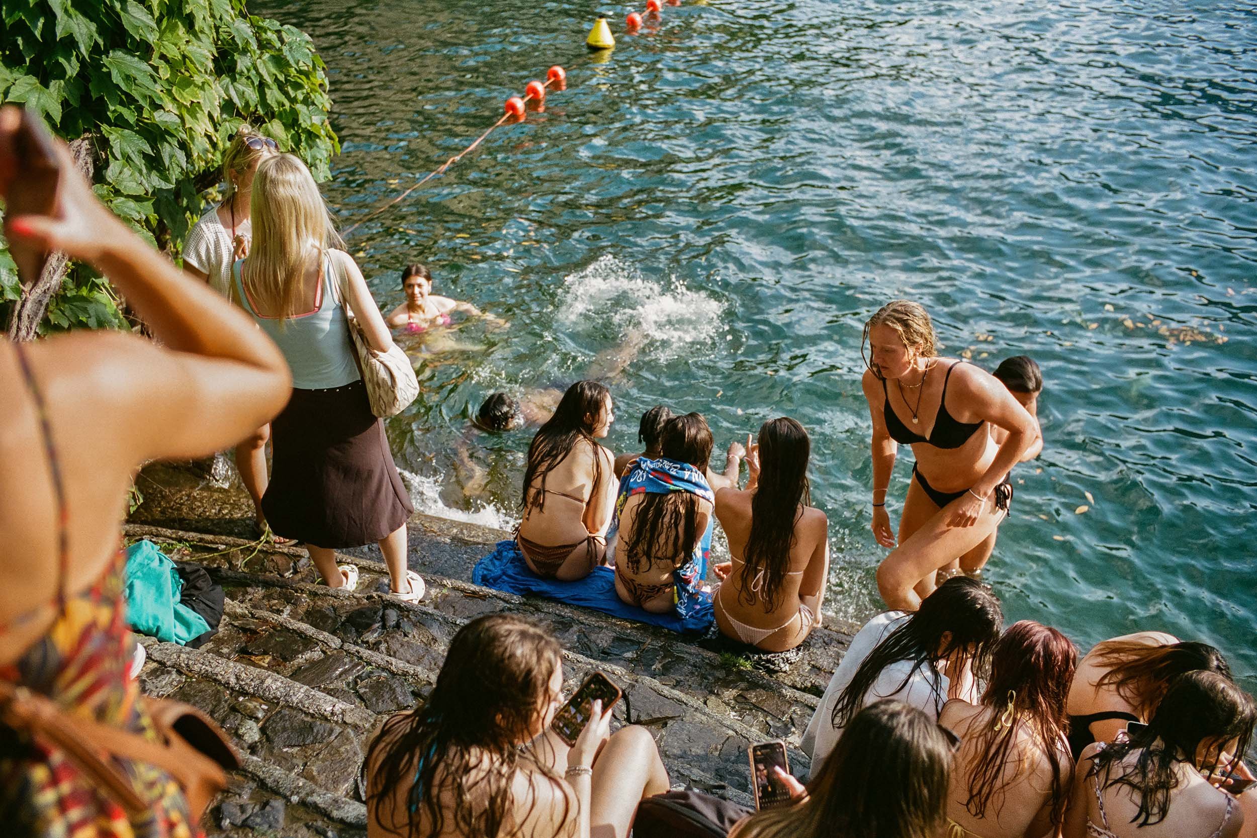 Junge Menschen baden am Ufer des Comer Sees.