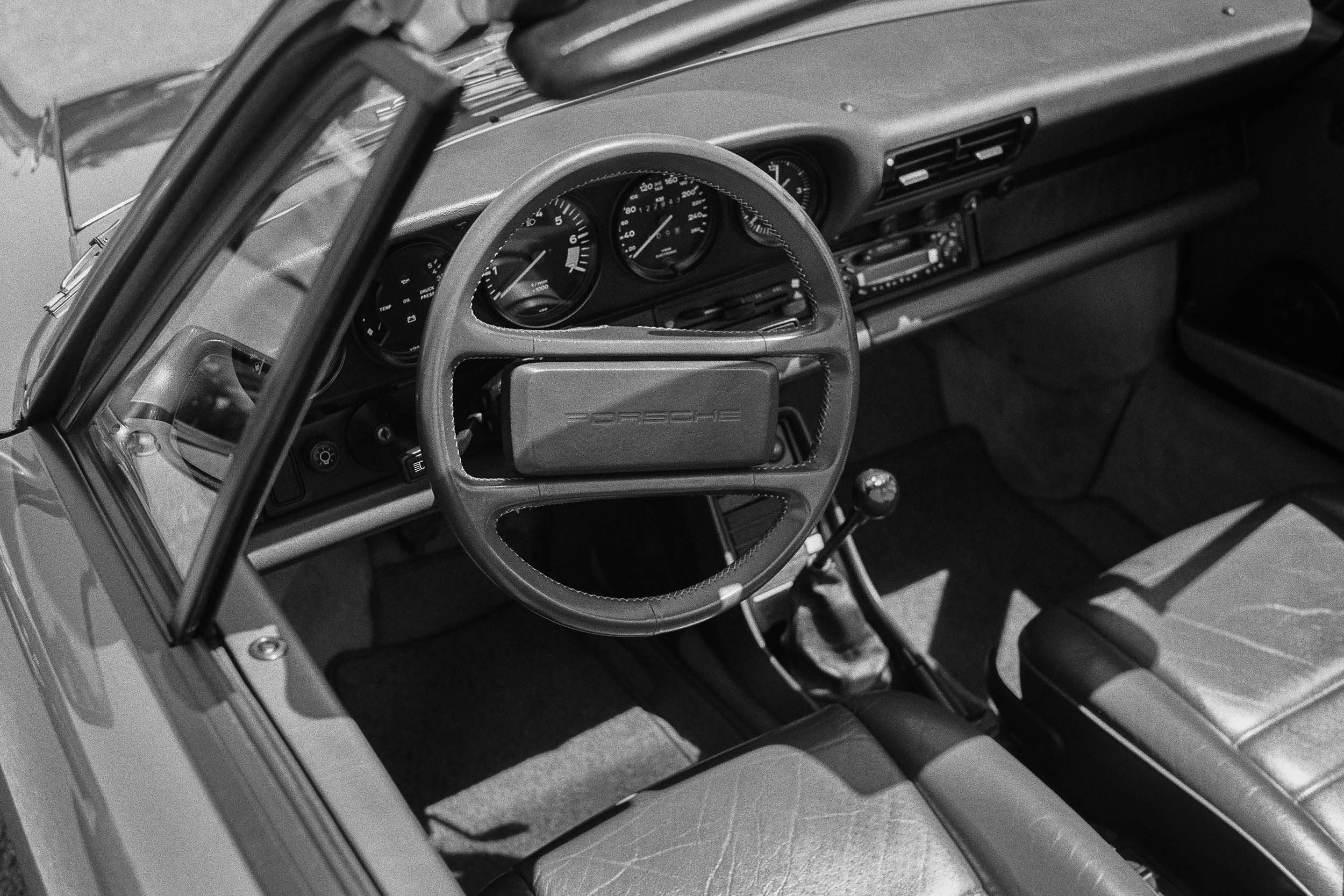 Detailaufnahme des Porsche-Innenraums mit Lenkrad und Instrumenten.