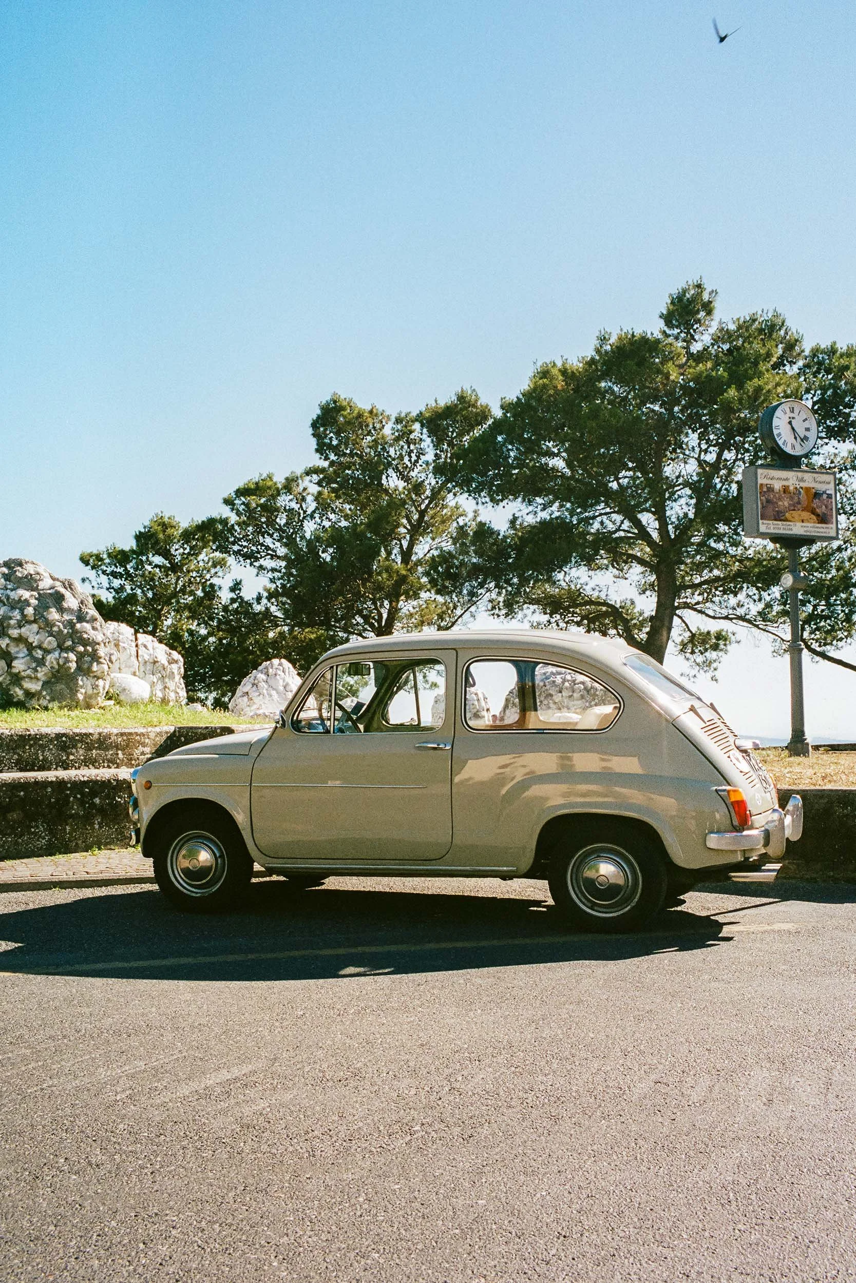 Klassischer Fiat 500 vor mediterraner Landschaft in der Toskana.