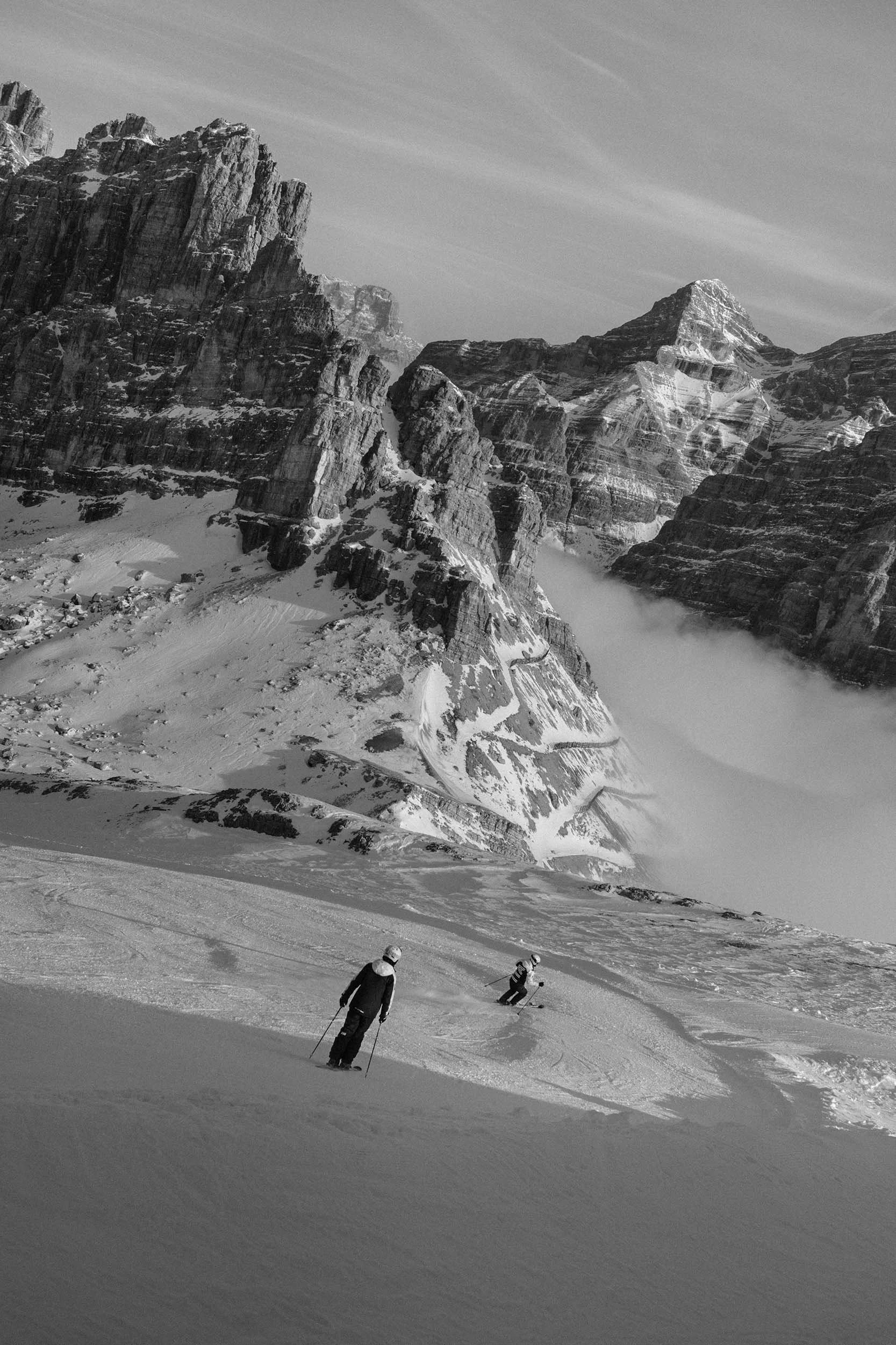 Zwei Skifahrer auf schneebedecktem Hang in den Dolomiten vor markanten Felsbergen