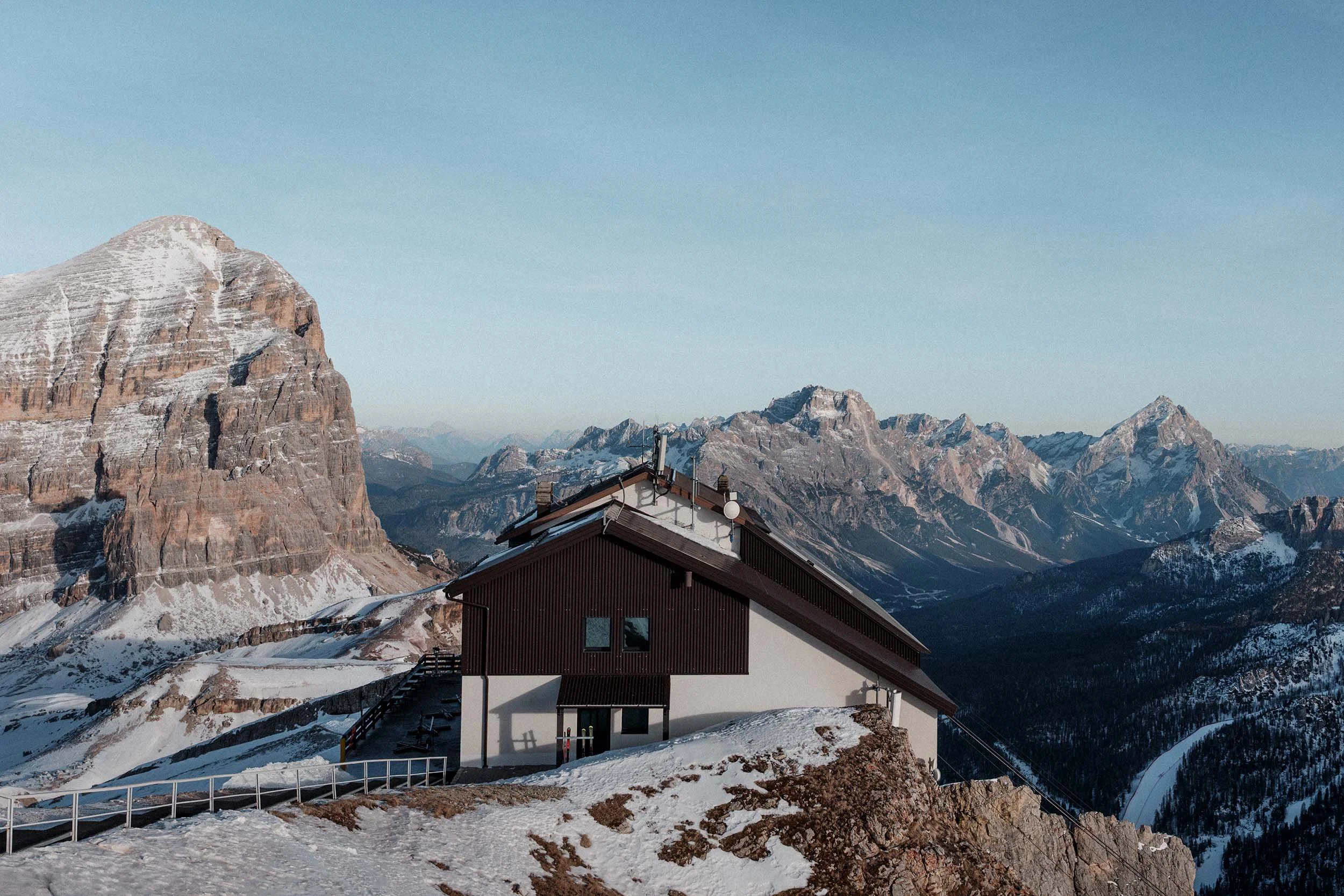 Berghütte in den Dolomiten auf verschneitem Berg mit Blick auf Felsgipfel