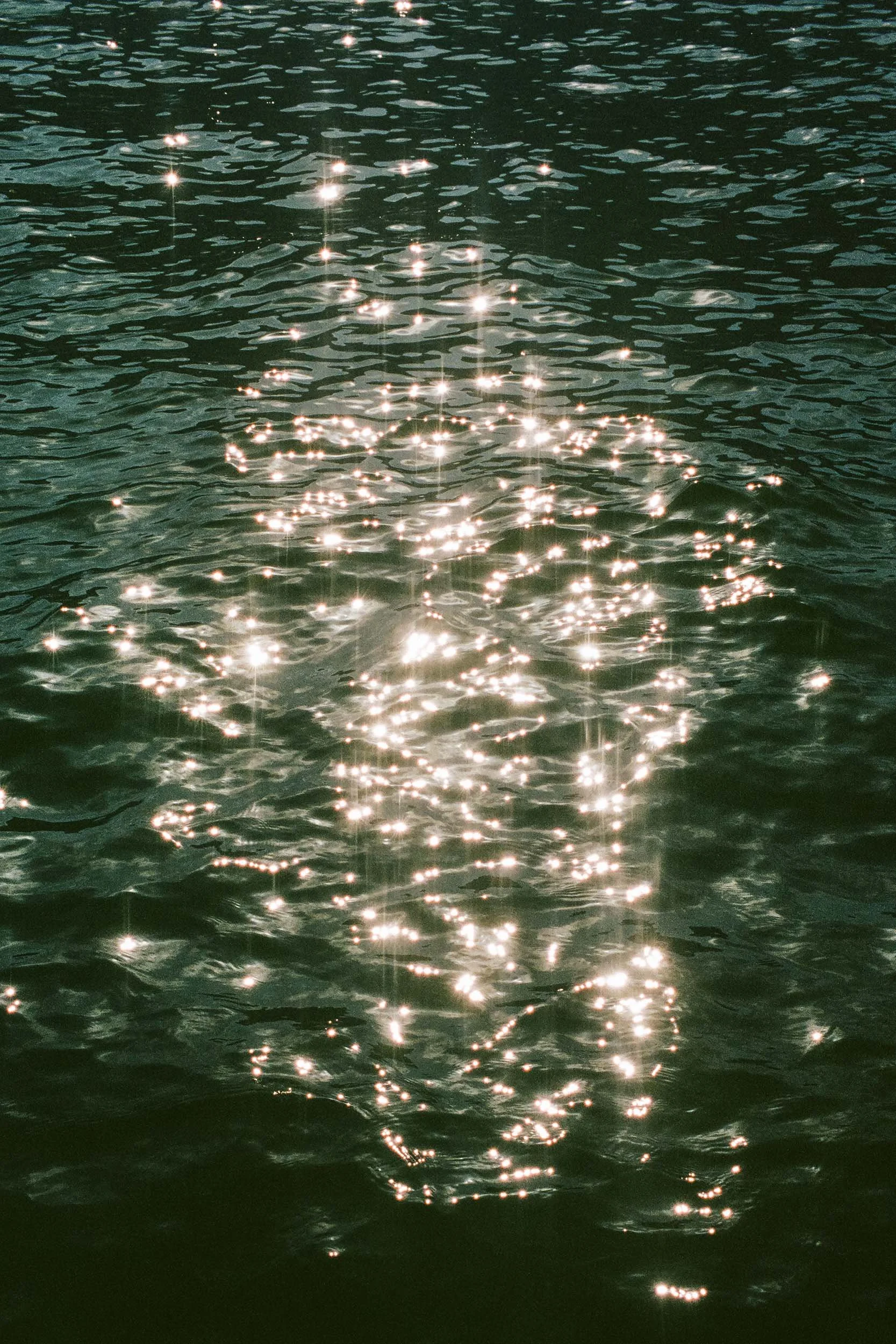 Sonnenlicht spiegelt sich auf der Wasseroberfläche des Comer Sees.