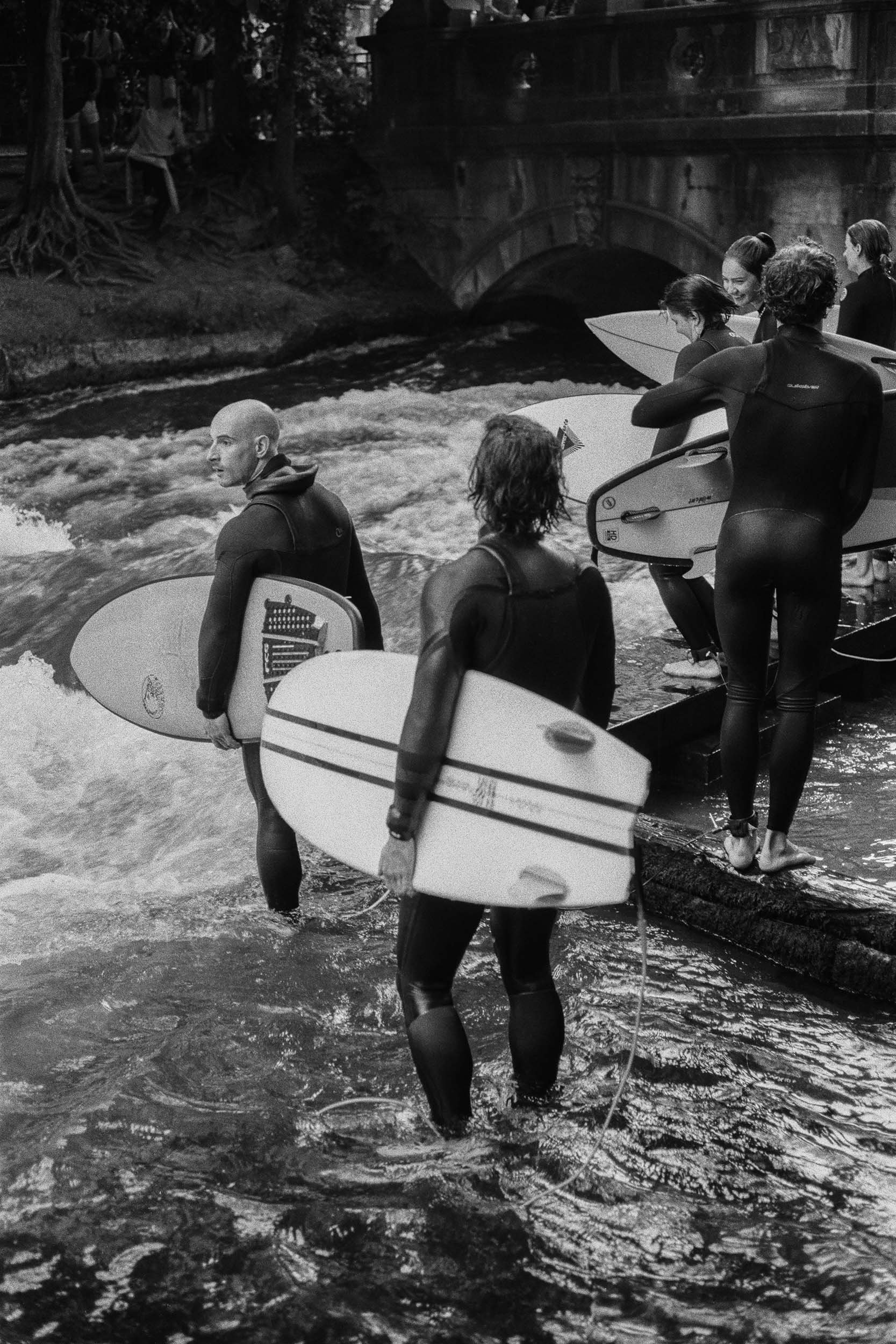 Surfer trägt sein Board durch die Eisbachwelle.