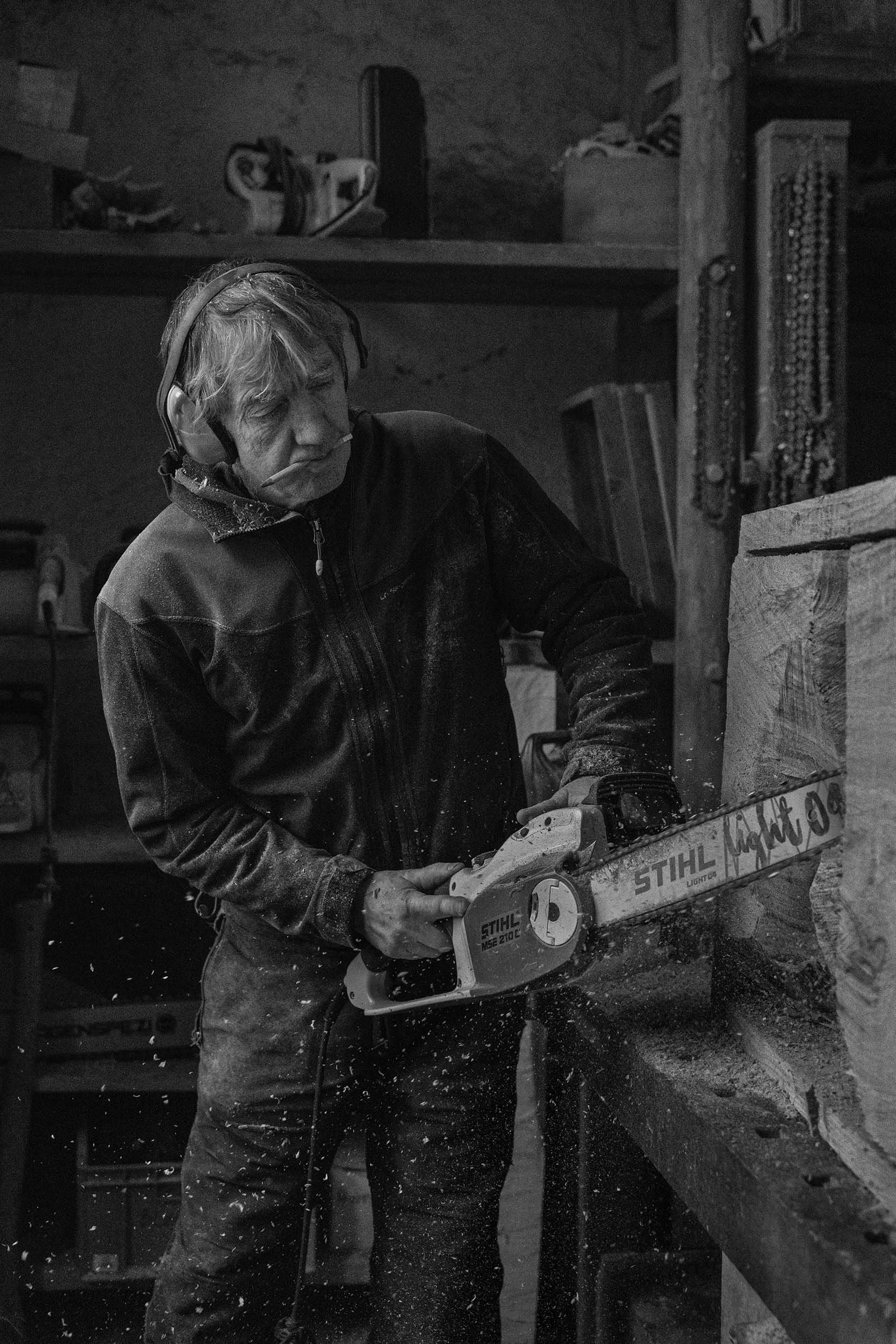 Ernst Groß bei Arbeit an Holzskulptur in Werkstatt