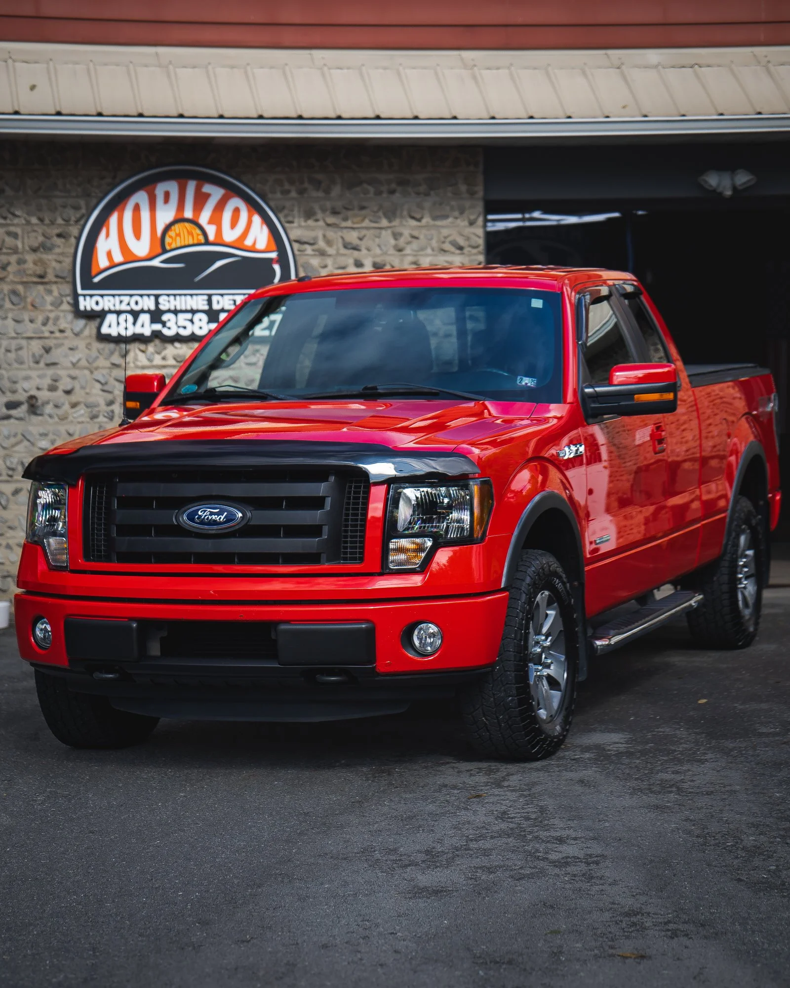 Red Ford pickup truck parked outside Horizon Shine Detailing shop.